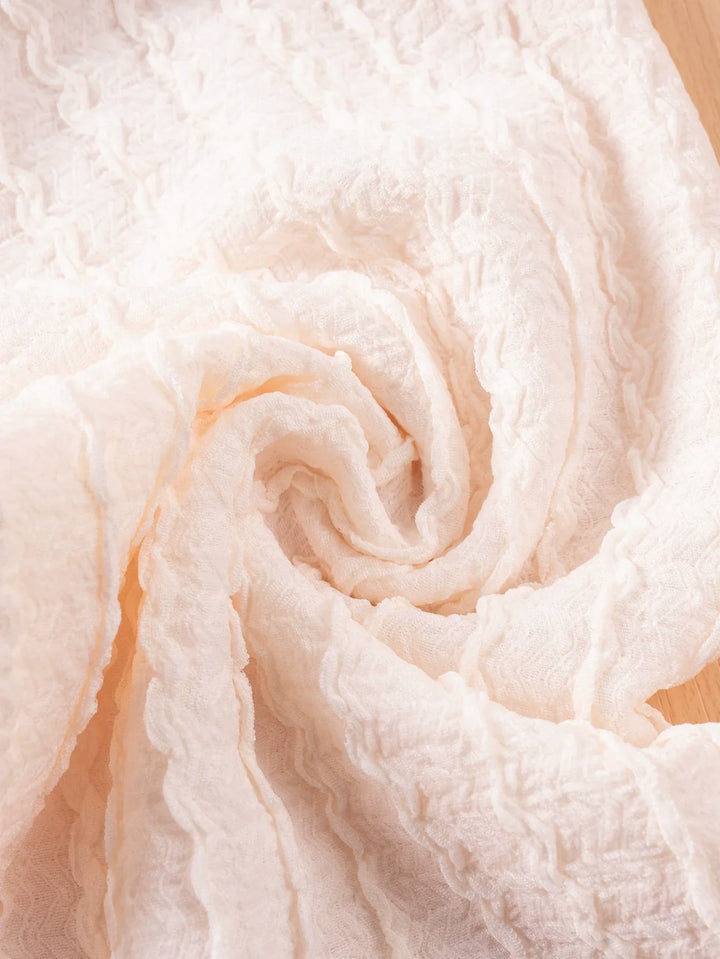 Close-up of soft, light pink fabric with a swirling pattern.