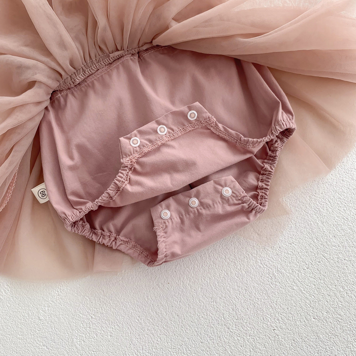 Pink baby bloomers with a sheer pink fabric background