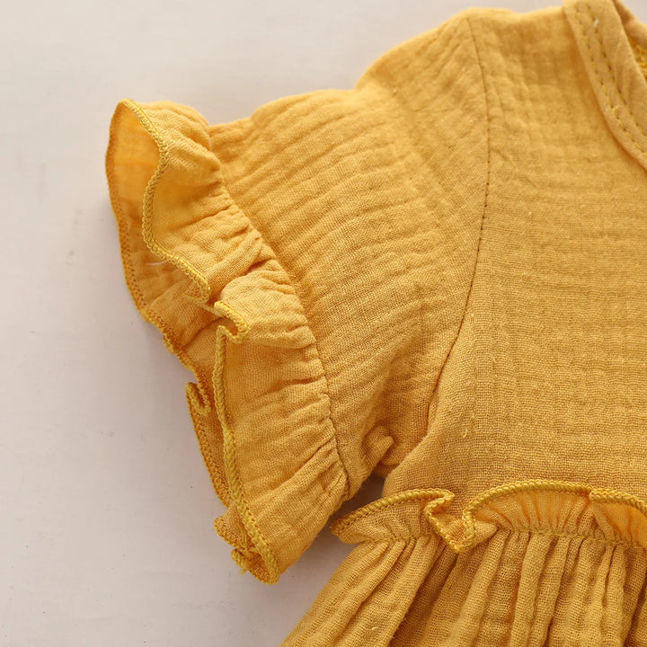 Yellow baby romper with ruffled details on a light background
