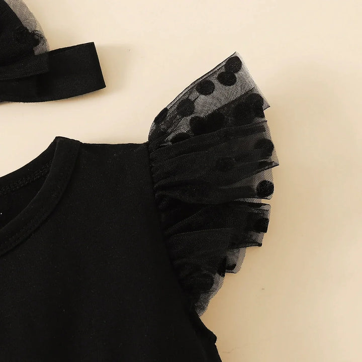 Black outfit with sheer ruffled sleeves on a beige background