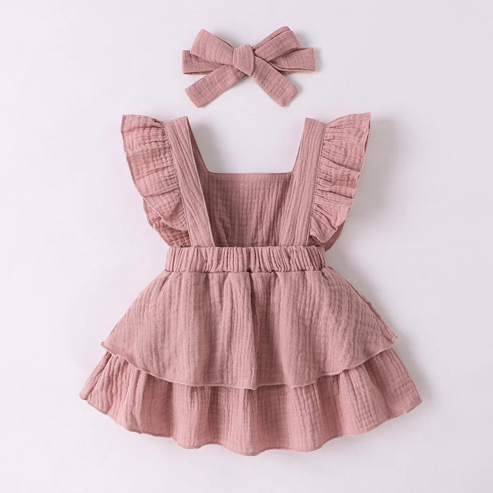 Pink ruffled dress with a matching headband on a white background