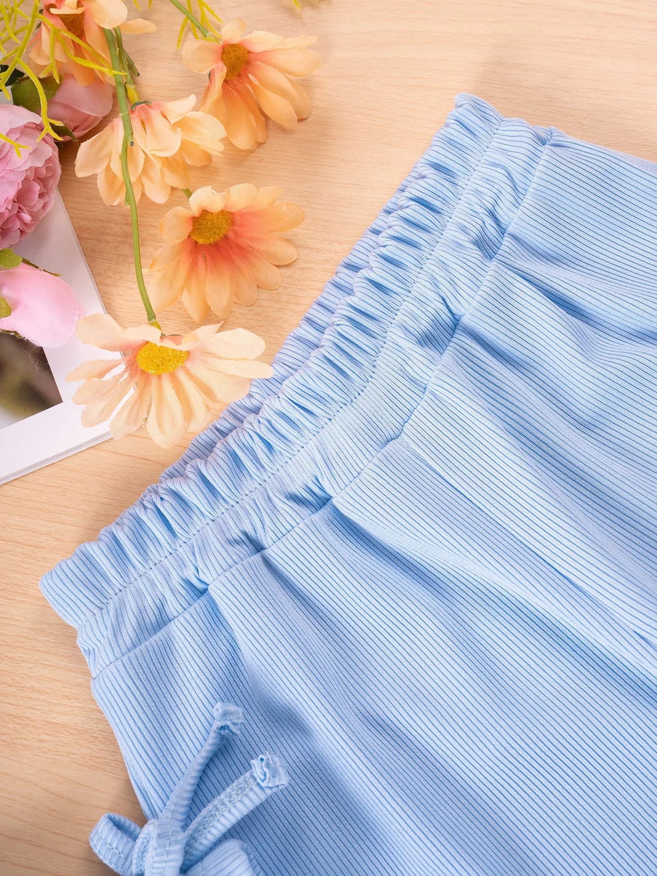 Close-up of a blue textured fabric with flowers in the background