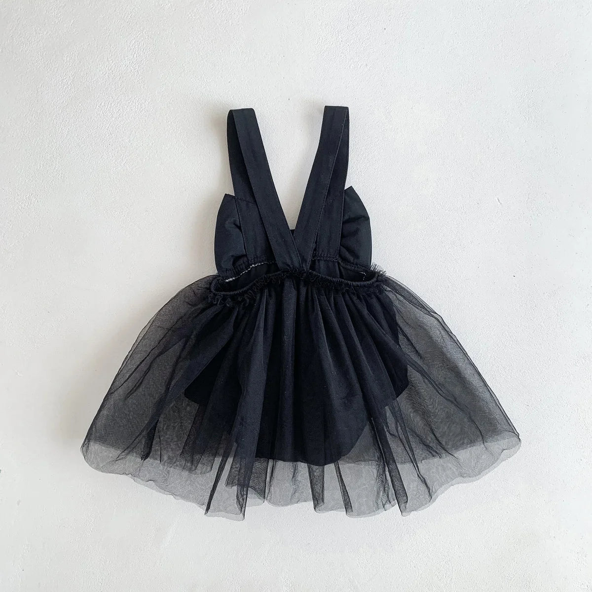 Black tulle dress with straps on a light gray background