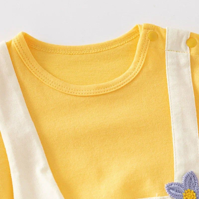 Close-up of a yellow and white outfit with a flower detail on a light gray background