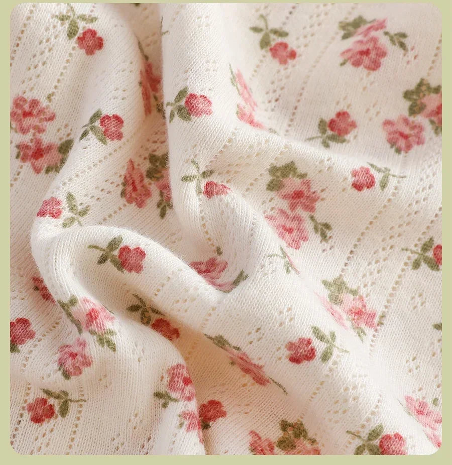 Floral patterned fabric with pink flowers and green leaves on a white background