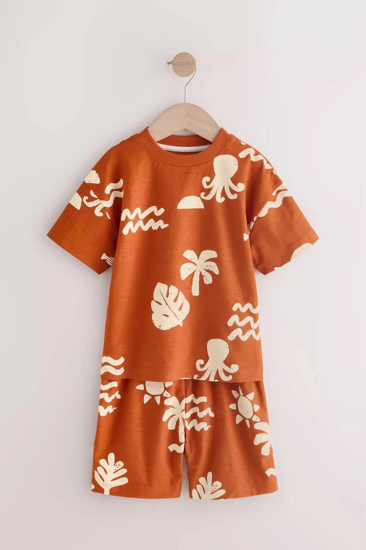 Children's orange outfit with white patterns on a hanger against a white background