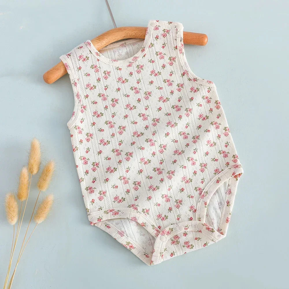 Floral-patterned baby romper on a wooden hanger against a light blue background