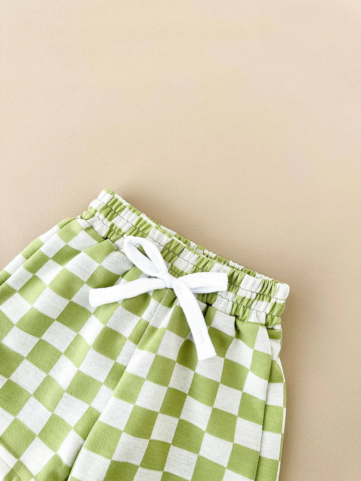 Green and white checkered shorts with a white drawstring on a beige background