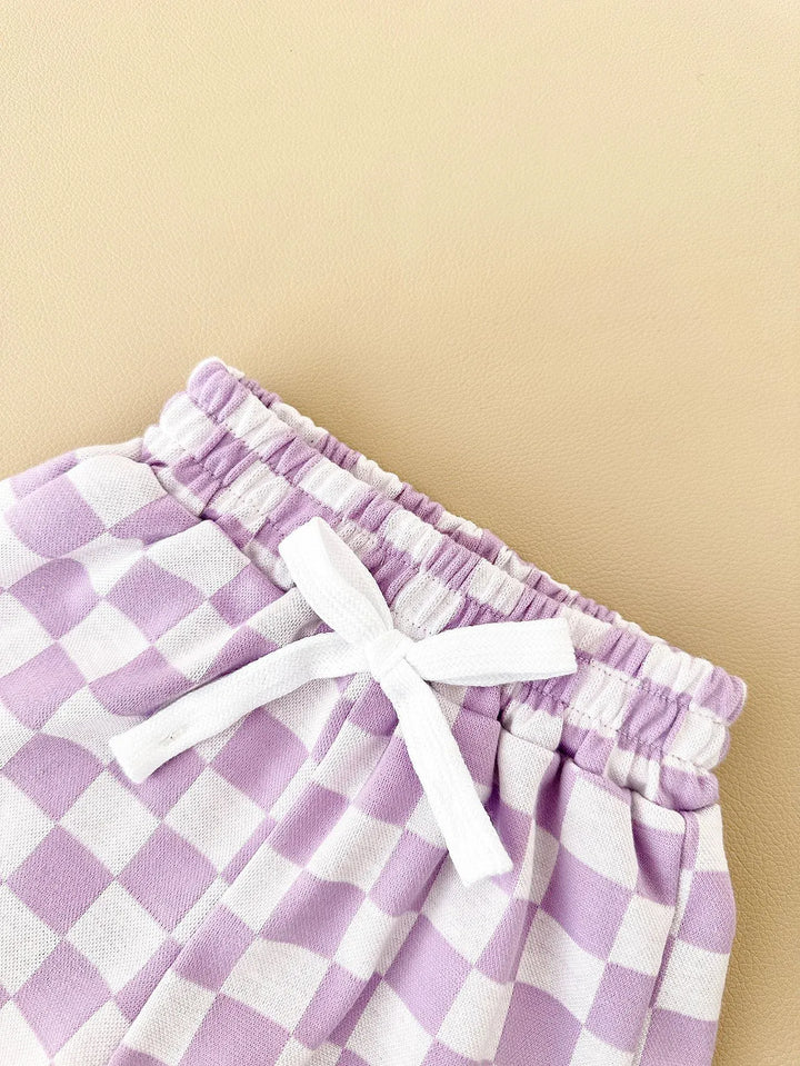 Purple and white checkered shorts with a white bow on a beige background