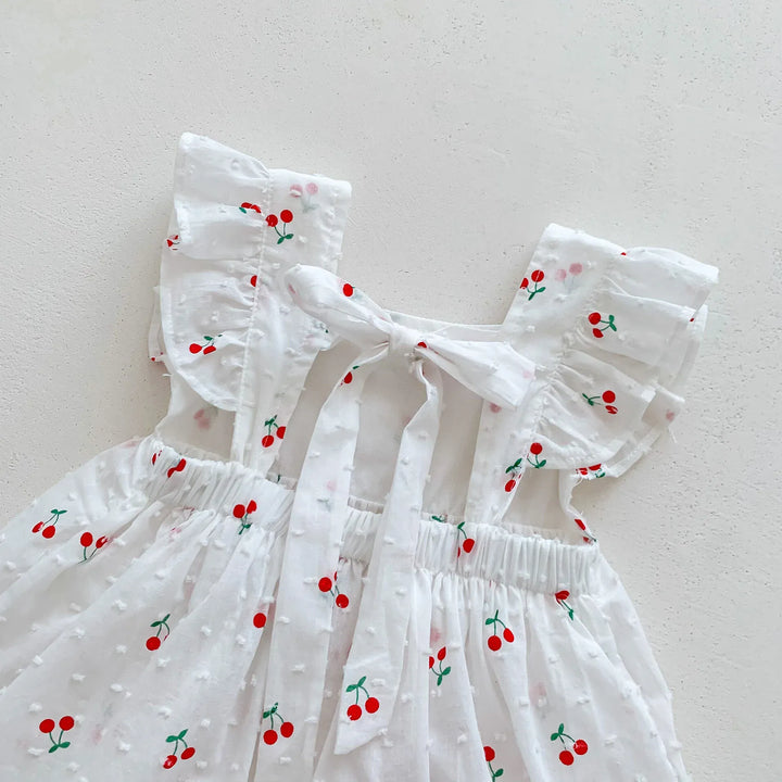 White dress with red cherry patterns on a light gray background