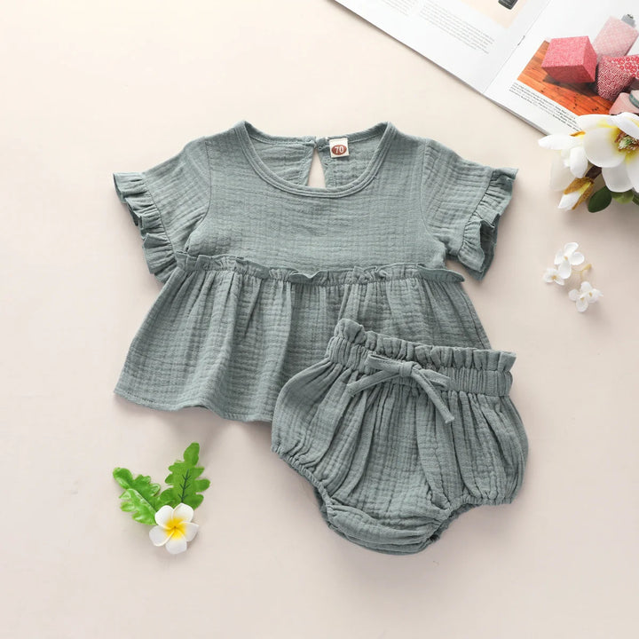 Green baby outfit with top and bloomers on a light background