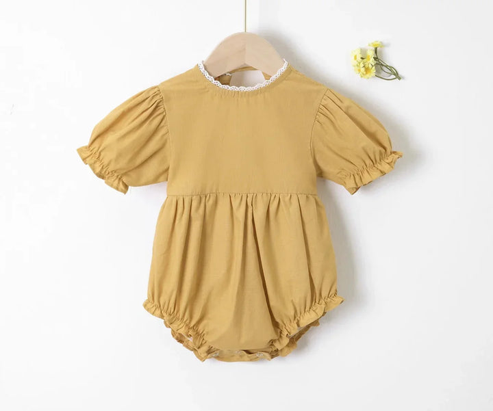 Yellow baby romper on a hanger against a white background
