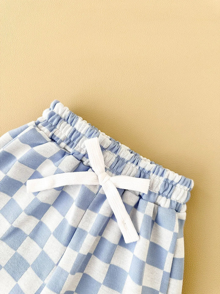 Blue and white checkered pants with a white drawstring on a beige background