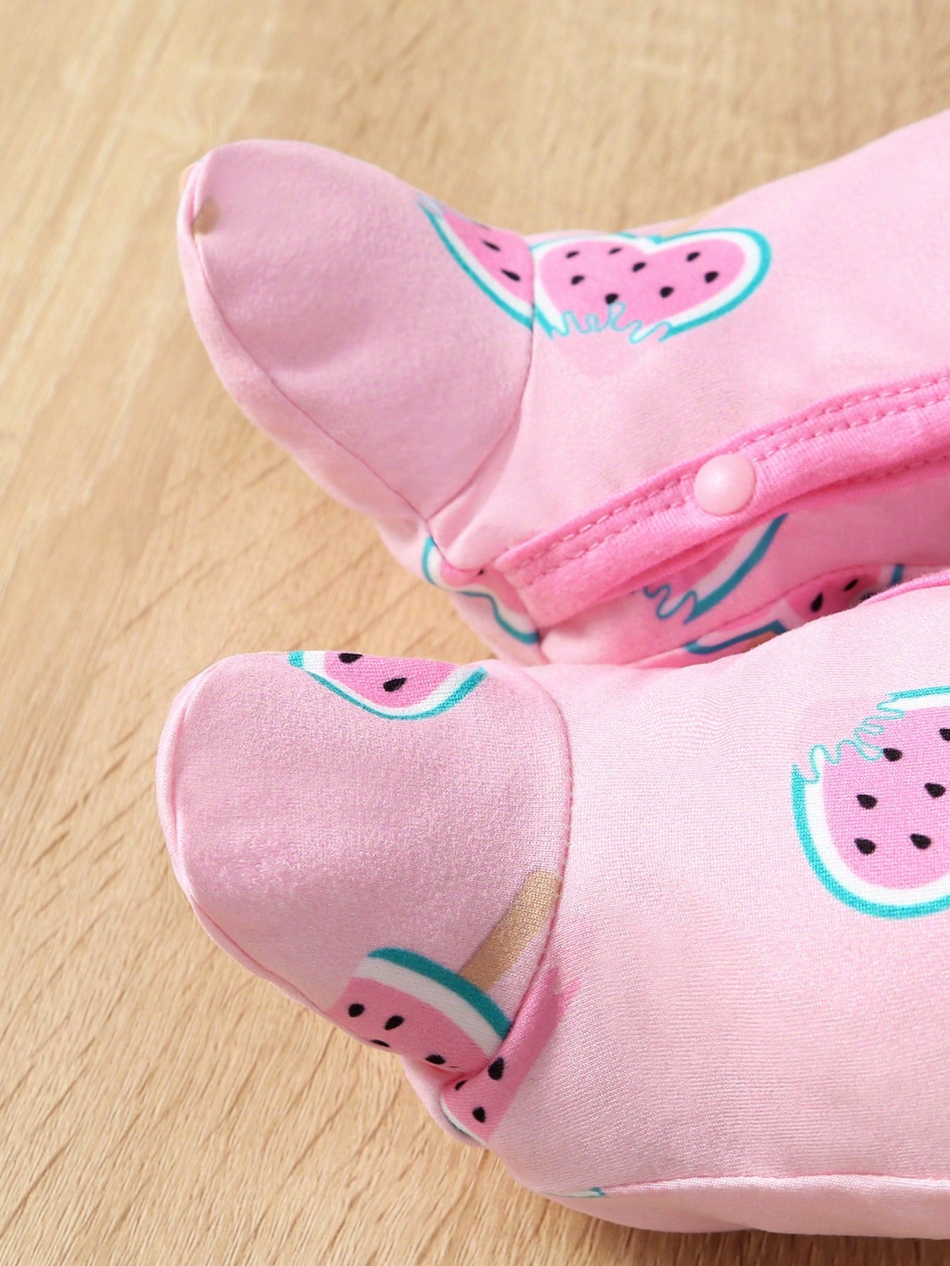 Pink children's shoes with watermelon pattern on a wooden floor