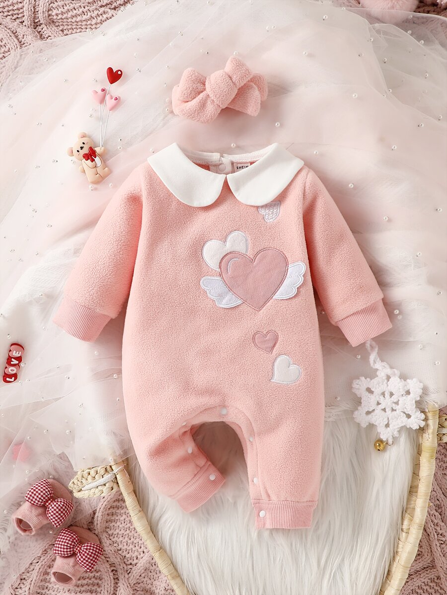 Pink baby romper with heart designs on a soft, textured background
