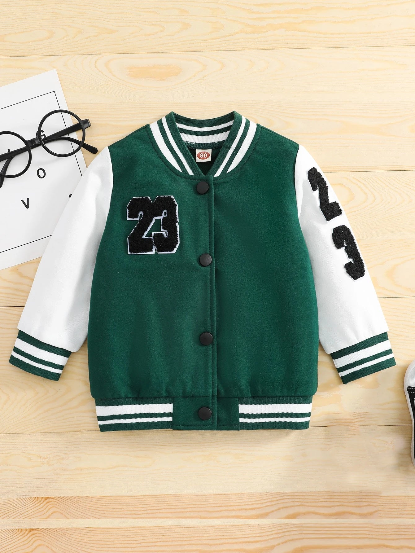 Green varsity jacket with number 23 on a wooden surface