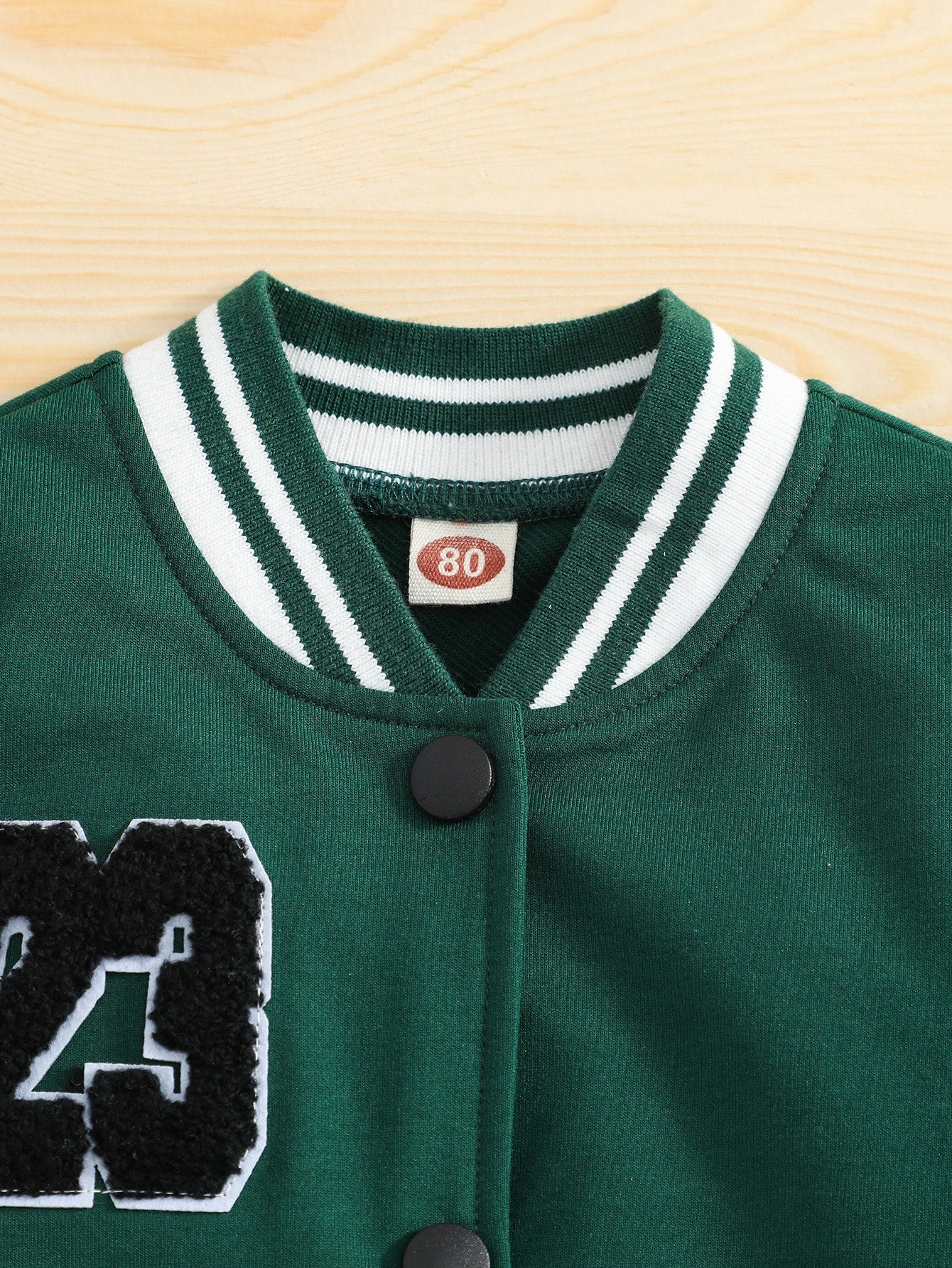 Green varsity jacket with white trim on a wooden surface