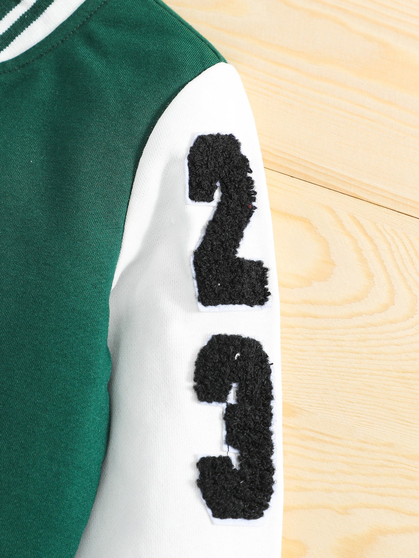 Green and white jacket with black numbers on a wooden surface