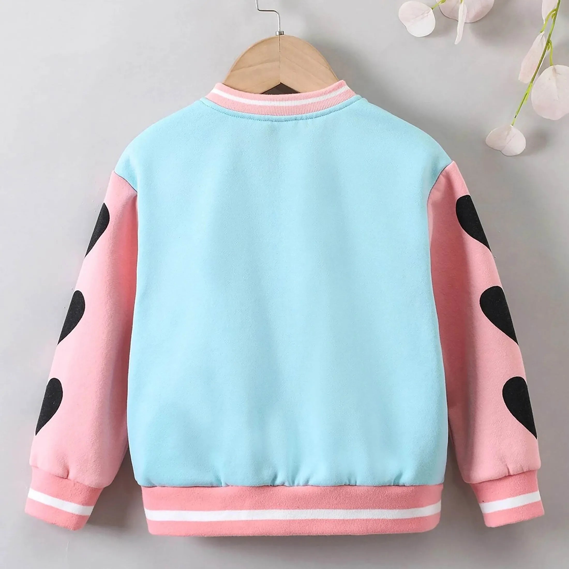 Children's jacket with pink and black polka dot sleeves on a gray background