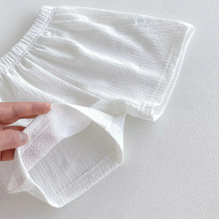 White fabric being held by a hand on a light gray background