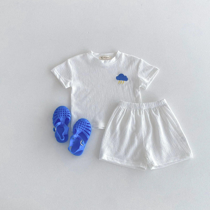 White children's outfit with blue sandals on a light gray background