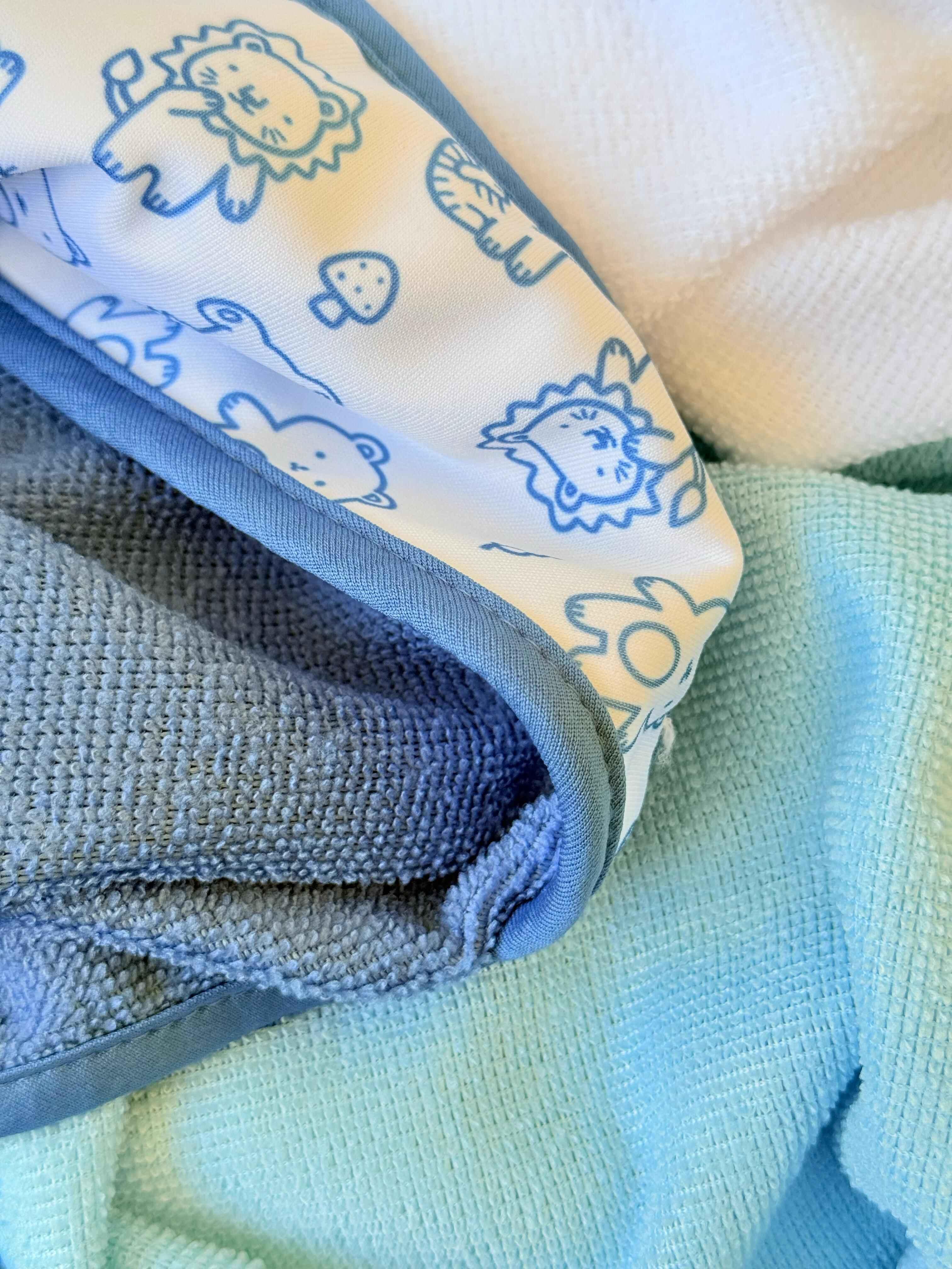Folded baby blanket with animal patterns on a textured surface