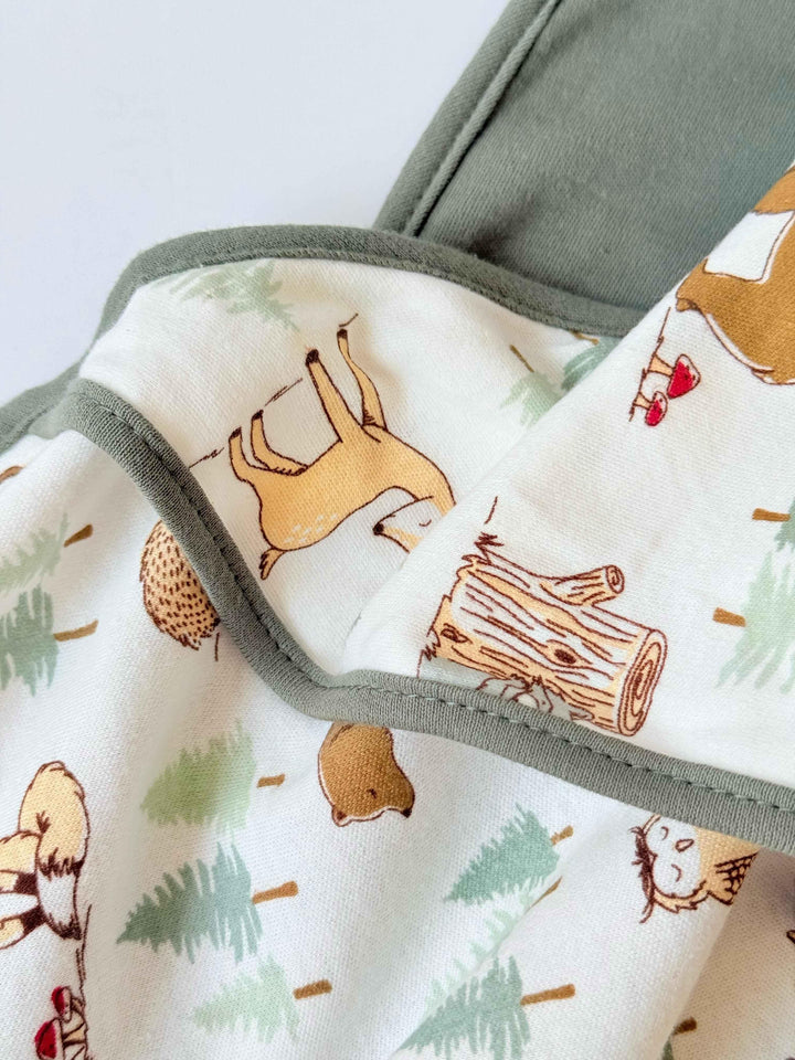 Fabric with forest-themed pattern featuring animals and trees on a white background