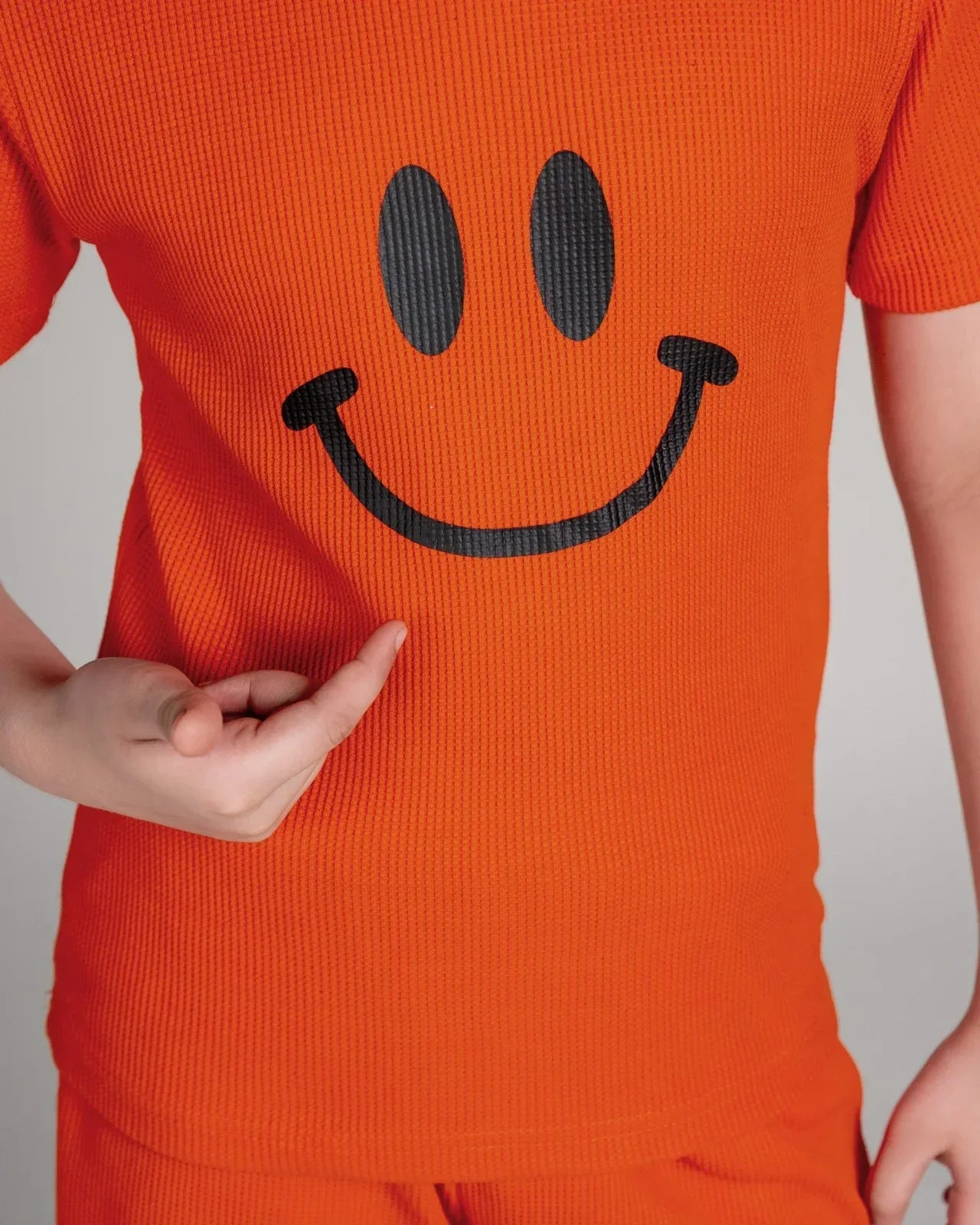 Person wearing an orange outfit with a smiley face design on a plain background
