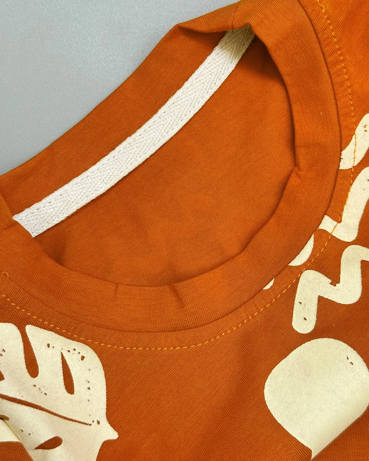 Close-up of an orange shirt with white patterns on a gray background