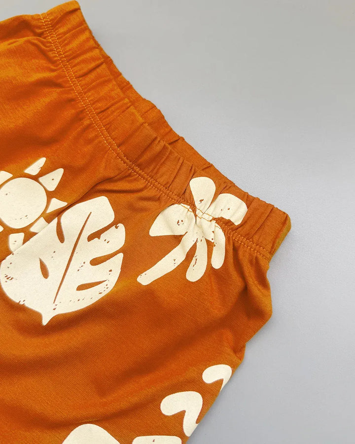 Orange shorts with white leaf patterns on a gray background