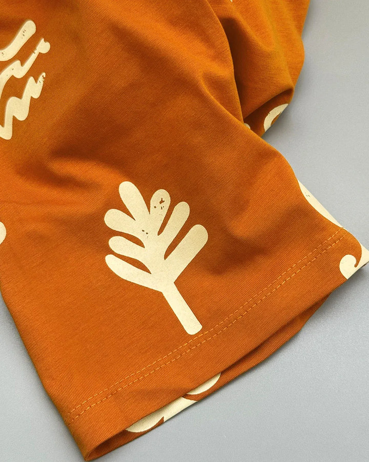 Orange fabric with white leaf pattern on a gray background