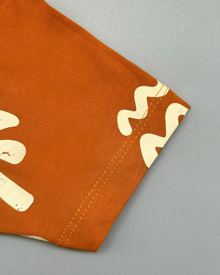 Corner of an orange fabric with white patterns on a gray background