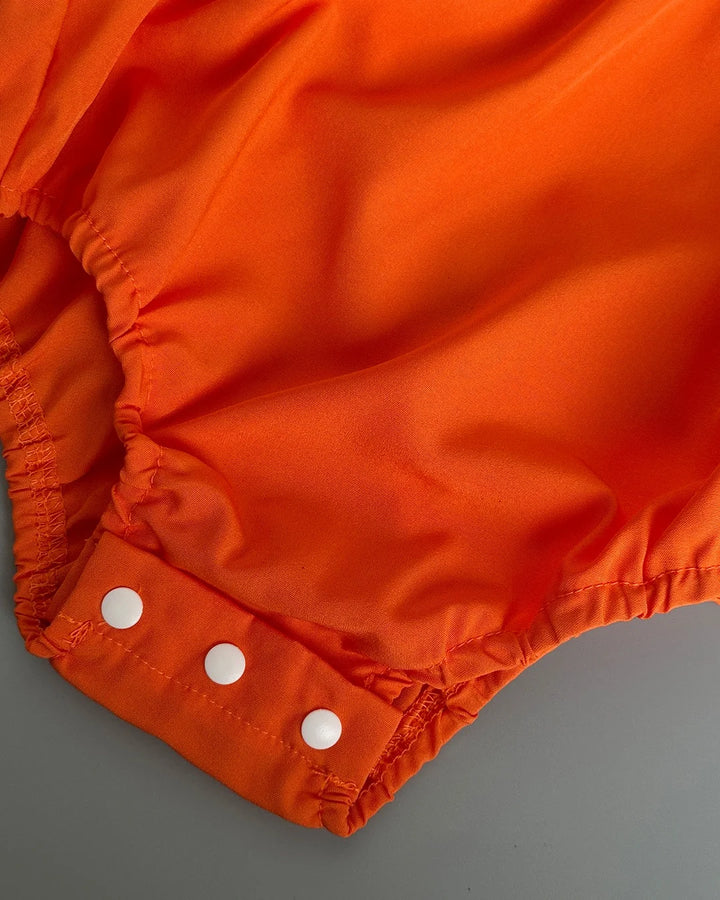 Close-up of orange fabric with white buttons on a gray background