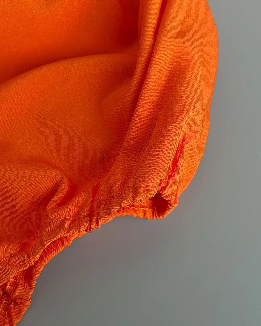 Close-up of an orange puffer jacket on a gray background