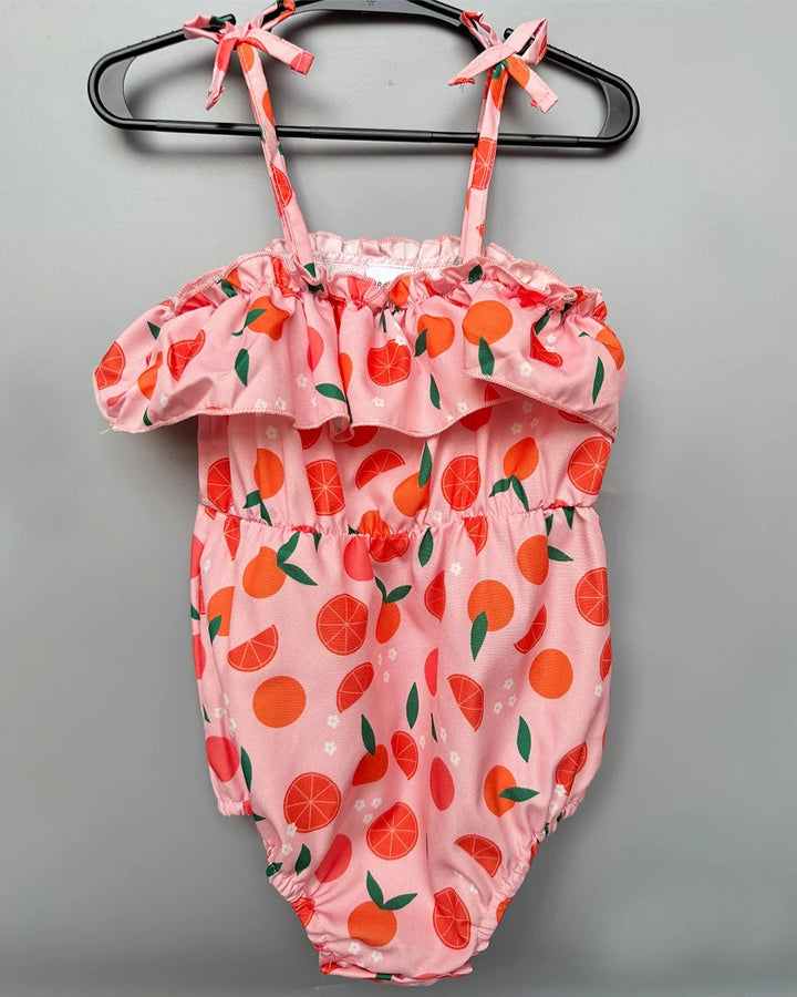 Pink baby romper with orange fruit pattern on a gray background