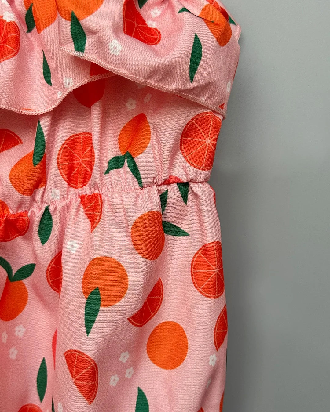 Pink dress with orange and green pattern on a gray background