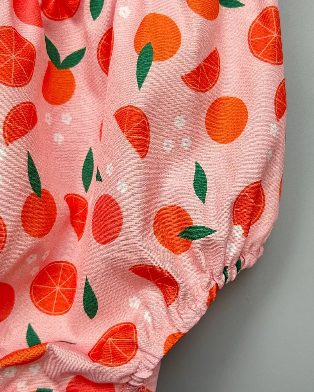 Pink shorts with orange and green pattern on a gray background