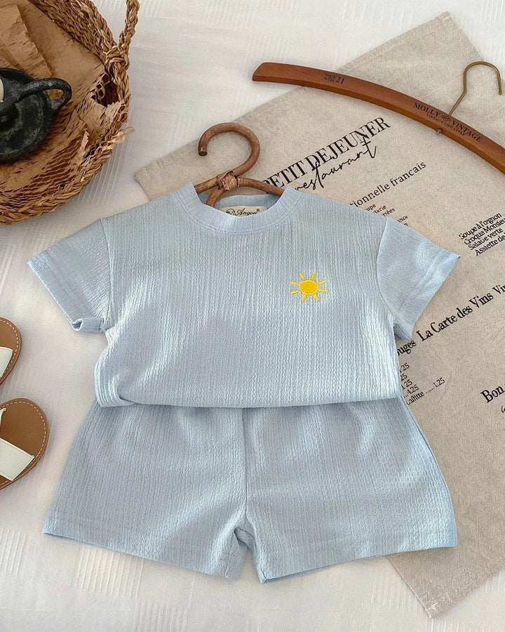 Children's light blue outfit with a sun design on a textured surface