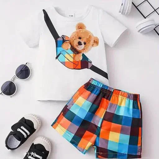 Children's outfit with a white t-shirt featuring a teddy bear graphic, colorful checkered shorts, and black sneakers on a white background.