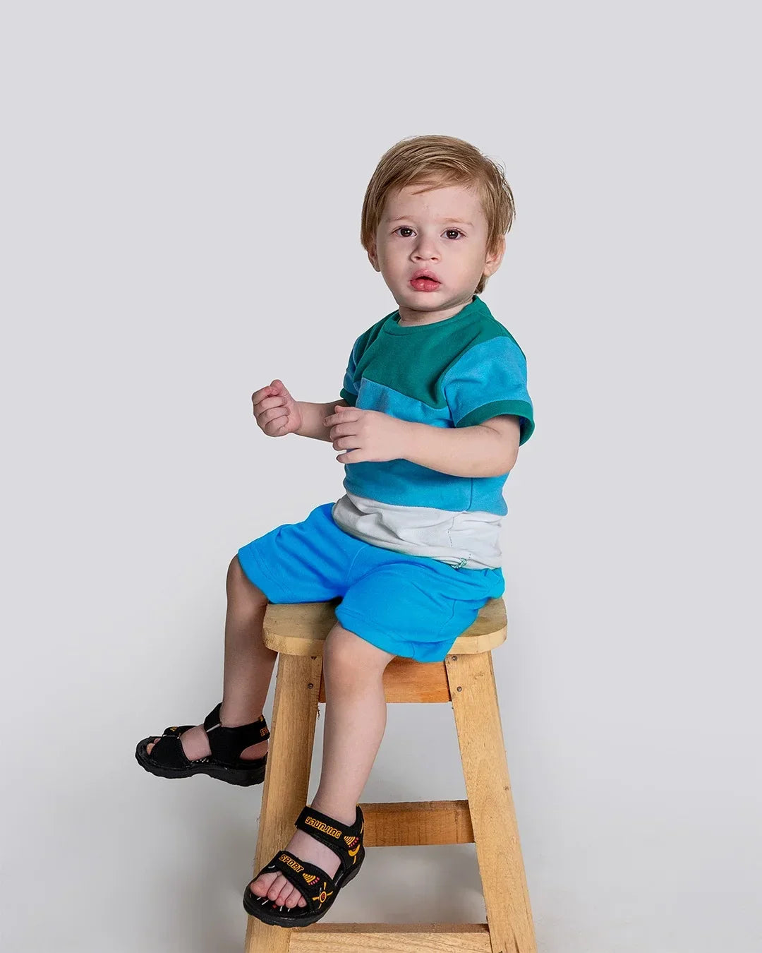 Child sitting on a wooden stool against a plain background