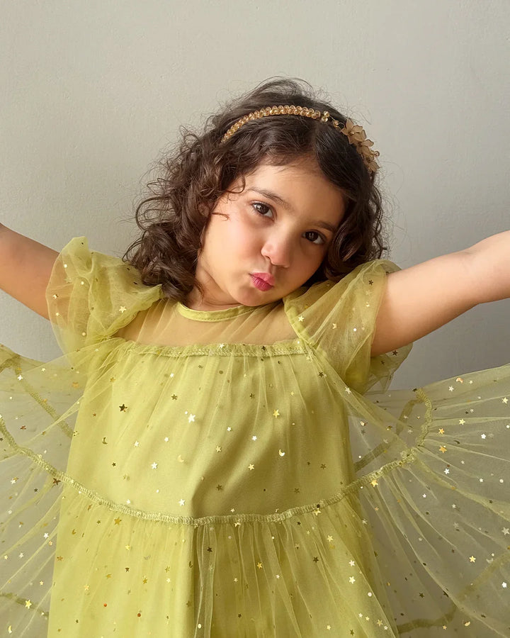 Young girl in a yellow dress with sheer sleeves and a plain background