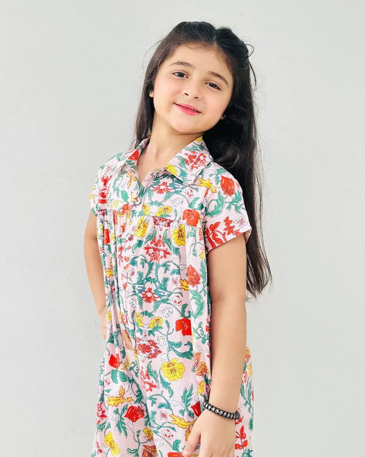 Young girl wearing a colorful floral dress against a plain background