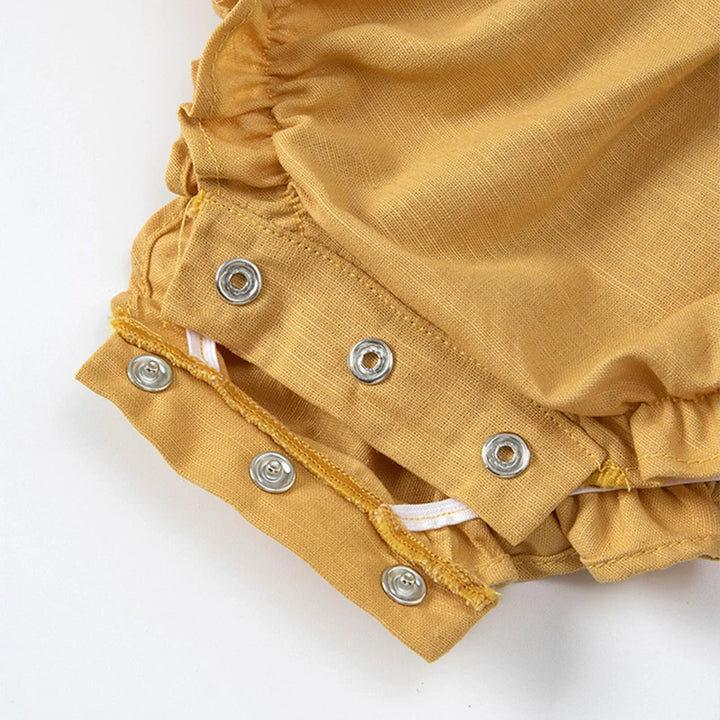 Mustard yellow baby bloomers with button details on a white background