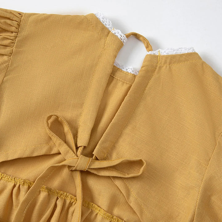 Mustard yellow top with lace trim on a white background