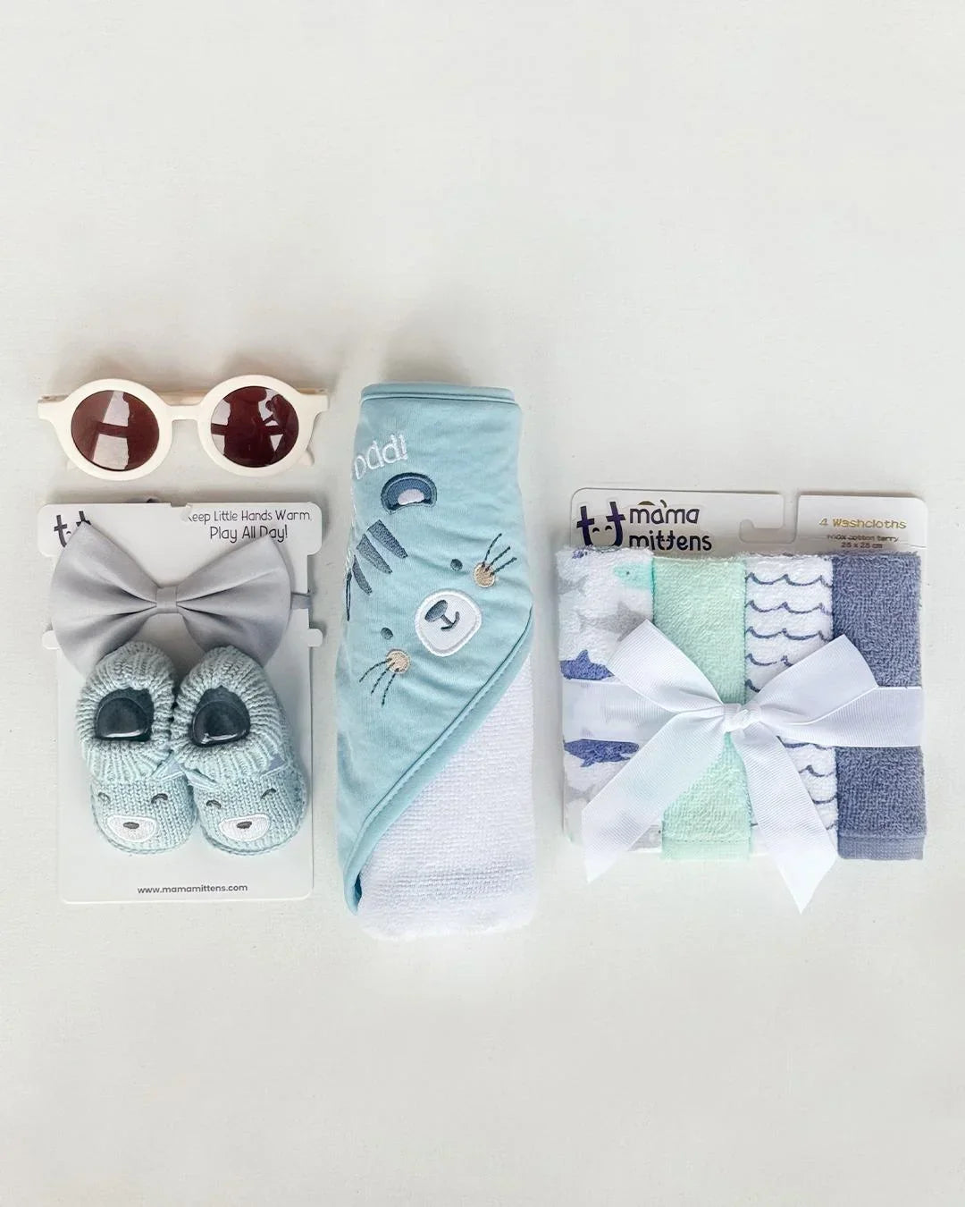 Baby gift set with sunglasses, socks, and other items on a white background