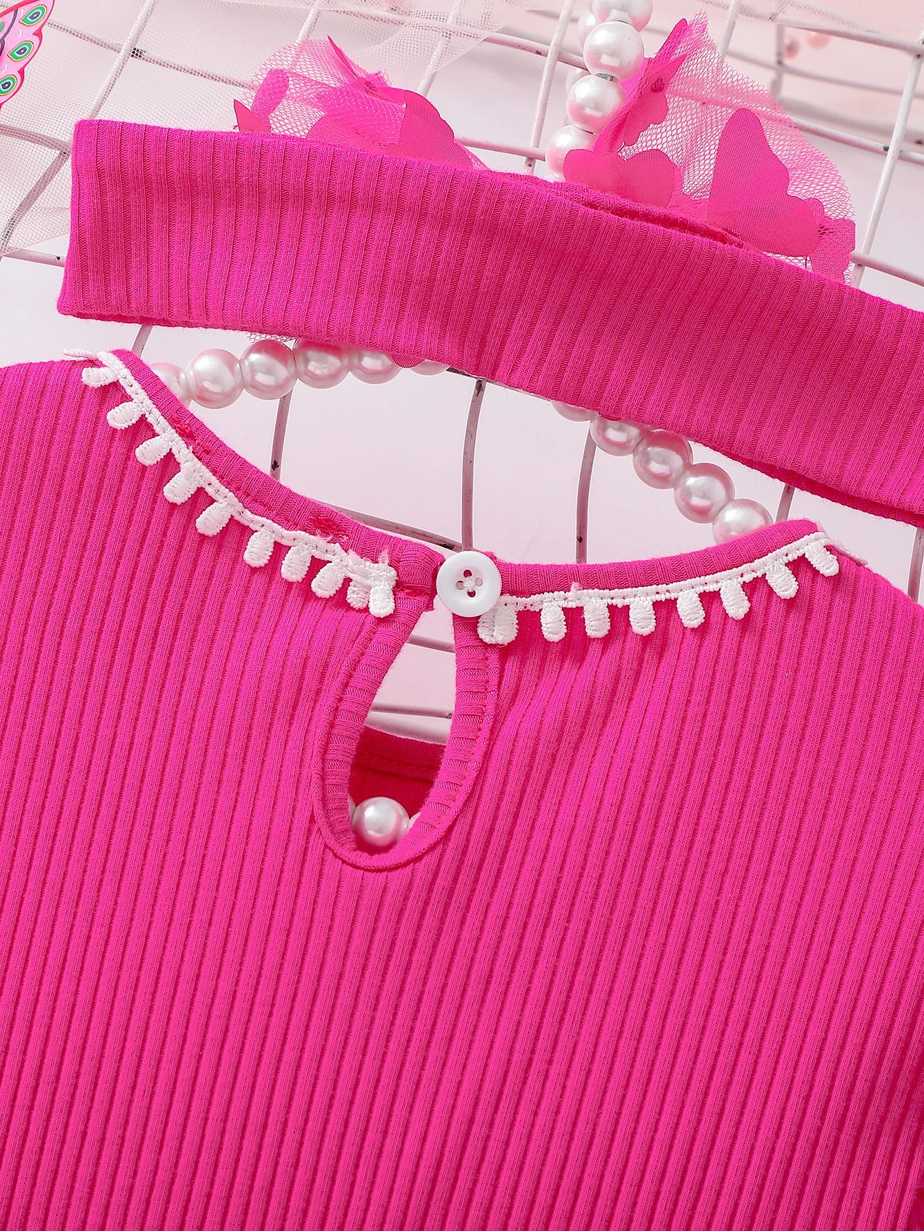 Close-up of a pink dress with white lace details on a white background