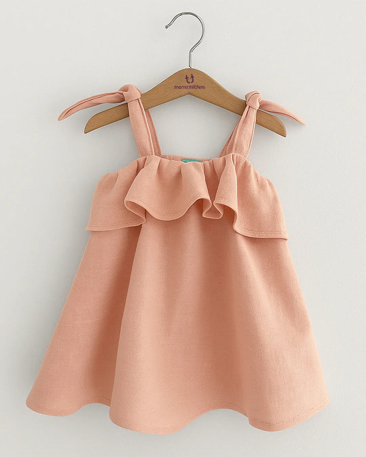 Pink dress with ruffled details on a hanger against a light gray background