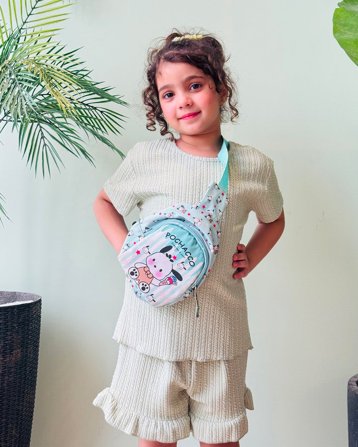 Child wearing a beige outfit with a colorful bag, standing against a light background with plants.