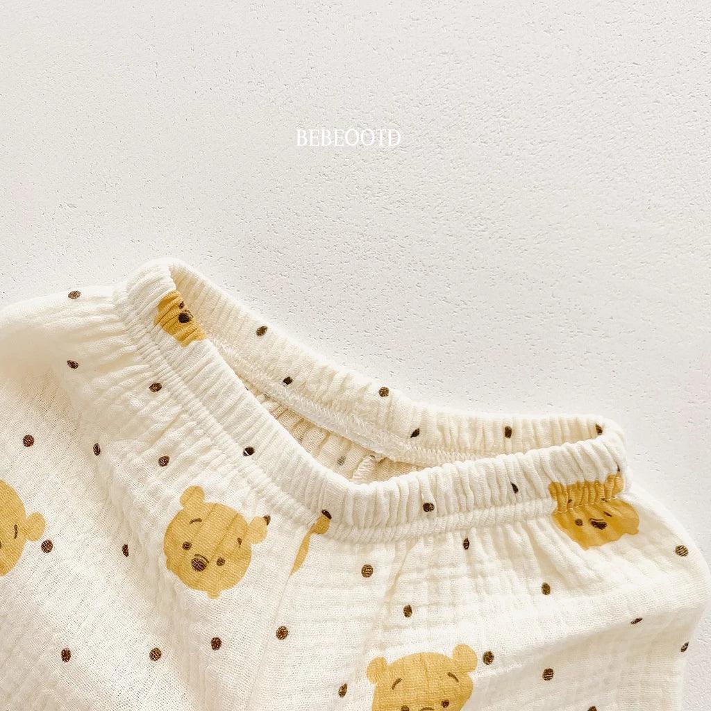 White baby pants with yellow bear faces and brown spots on a light gray background