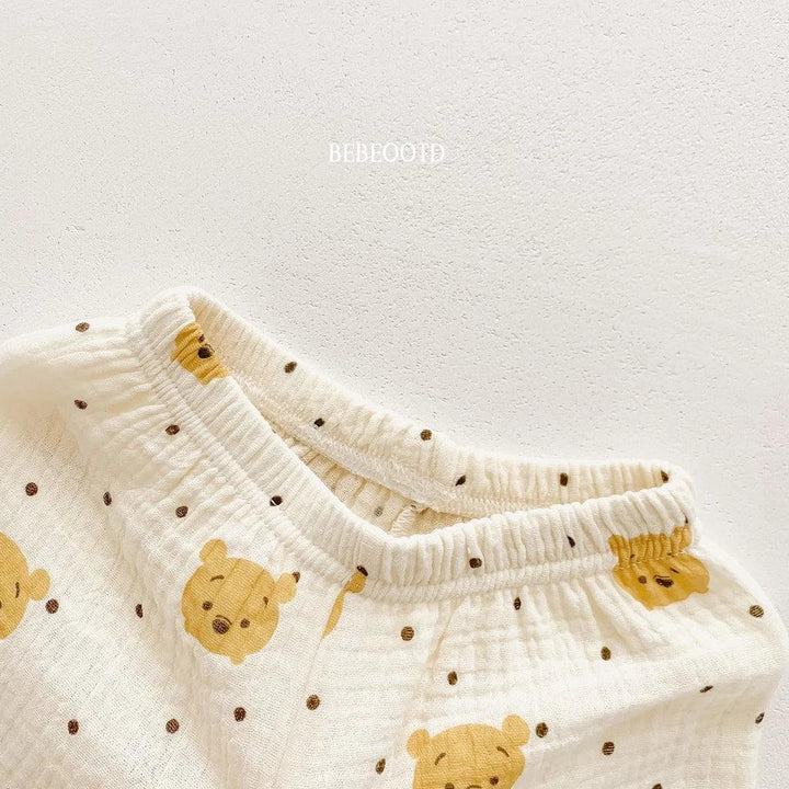 White baby pants with yellow bear faces and brown spots on a light gray background